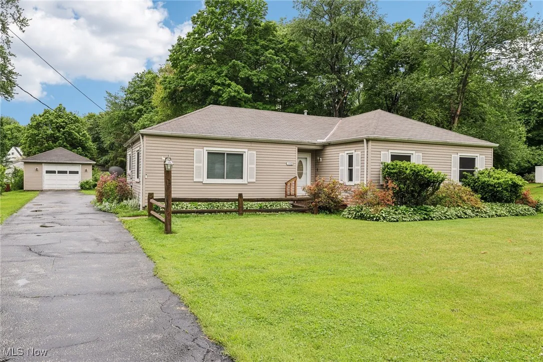View of front of house featuring a garage, a front lawn, and an outbuilding