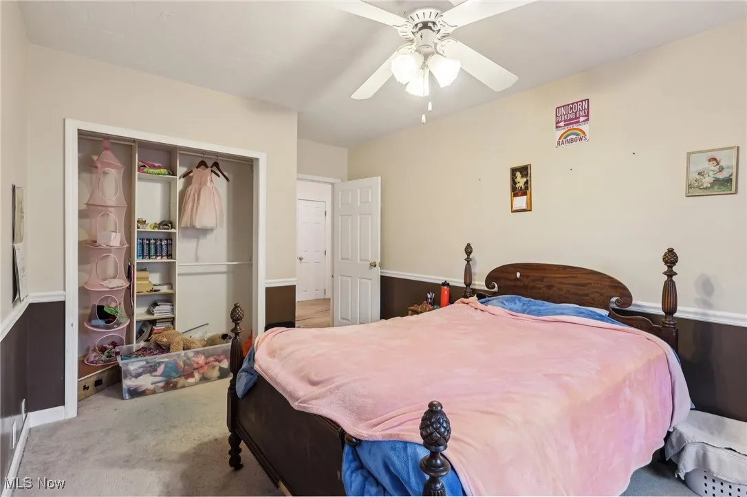 Carpeted bedroom with baseboards, ceiling fan, and a closet