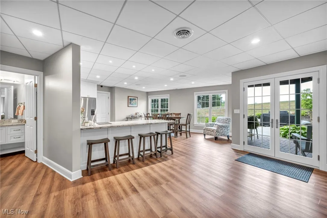 Kitchen featuring white cabinets, a kitchen breakfast bar, light stone countertops, a peninsula, and light wood finished floors