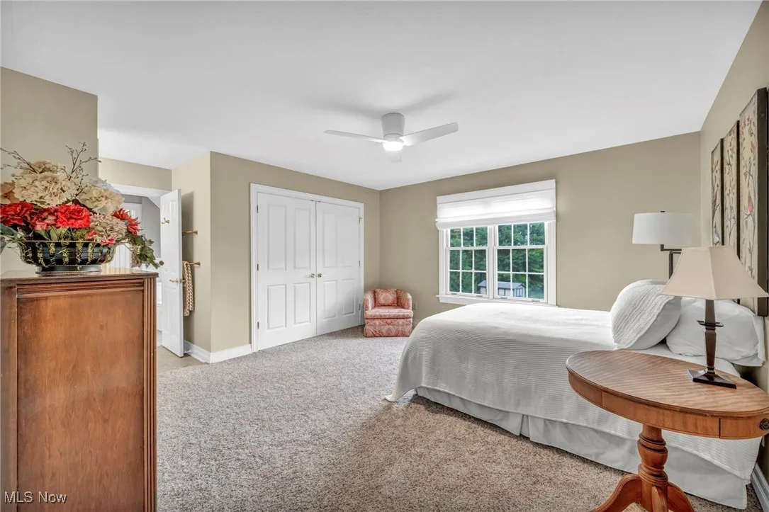 Bedroom with light colored carpet, ceiling fan, and a closet