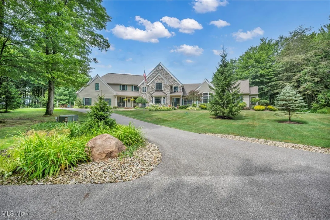 View of front of property featuring stone siding, a front yard, and covered porch