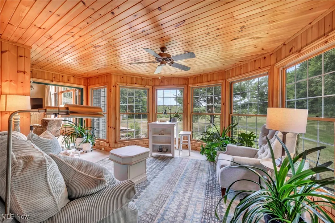 Sunroom with wooden ceiling, healthy amount of natural light, and wooden walls