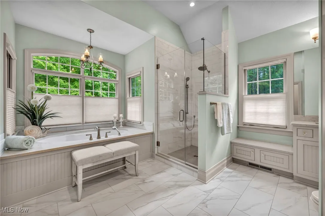 Full bathroom featuring a garden tub, a shower stall, light marble finish floors, a chandelier, and recessed lighting