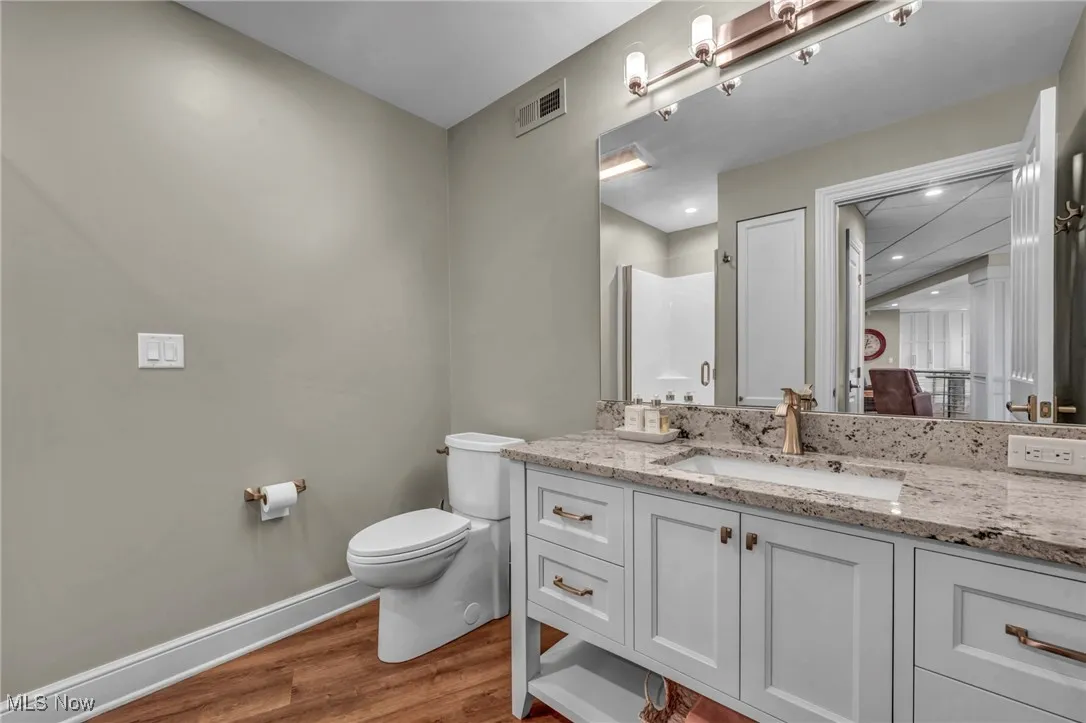 Full bath with vanity, dark wood-style flooring, and a shower stall