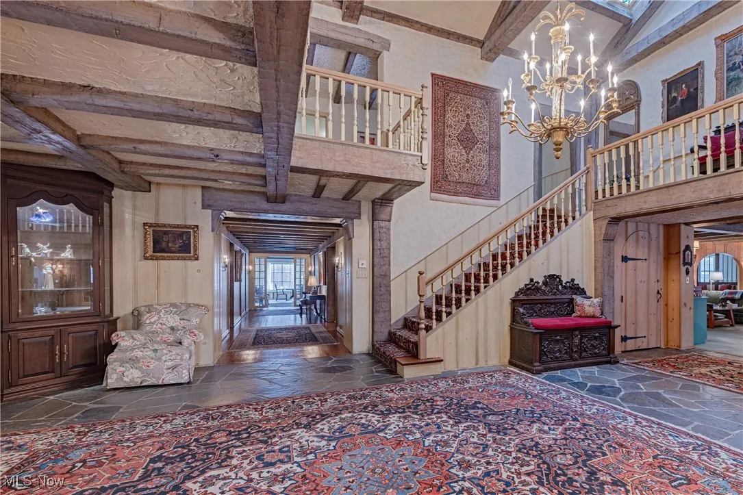 Stairway featuring dark tile flooring, an inviting chandelier, and beam ceiling