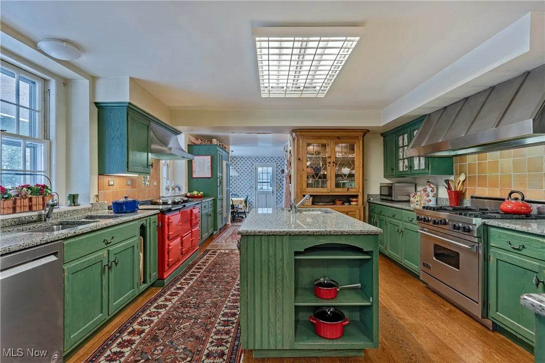 Kitchen with sink, green cabinetry, appliances with stainless steel finishes, dark hardwood / wood-style floors, and backsplash