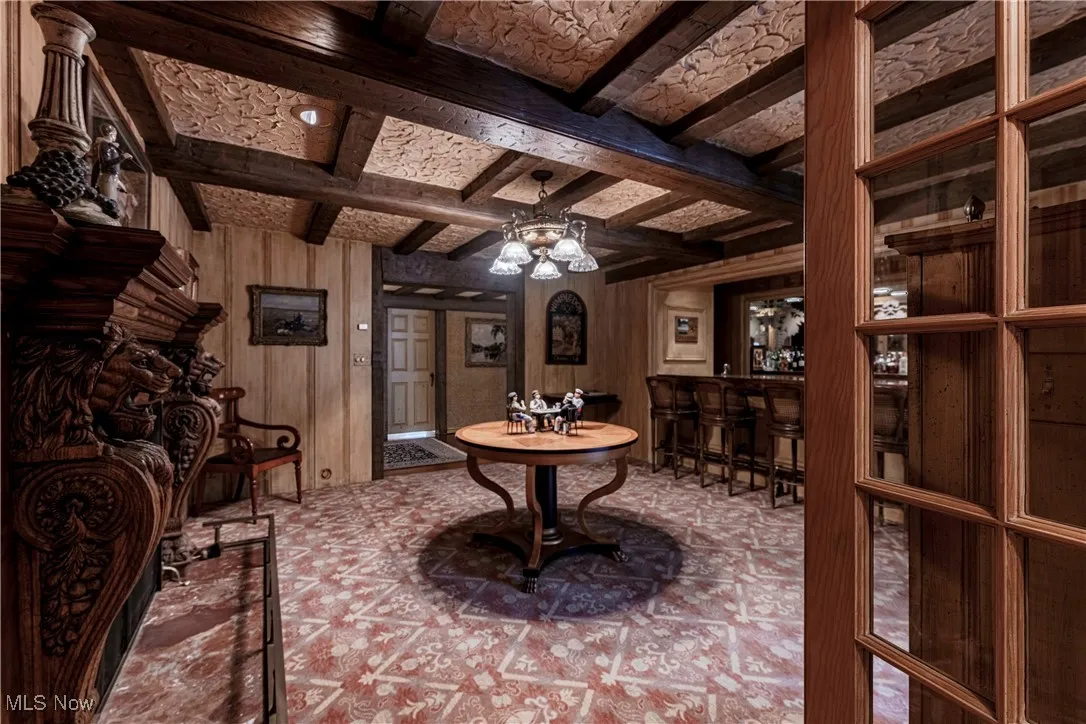 Playroom featuring coffered ceiling, ceiling fan, indoor bar, wood walls, and beam ceiling