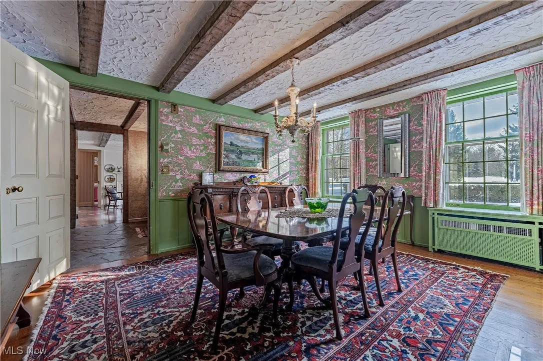 Dining area featuring a healthy amount of sunlight, an inviting chandelier, radiator, and hardwood / wood-style flooring