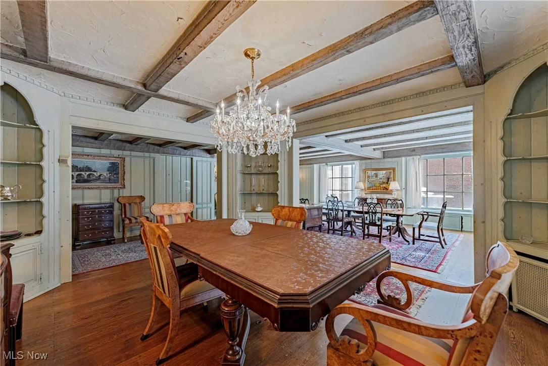 Dining room with dark hardwood / wood-style flooring, a chandelier, and beamed ceiling