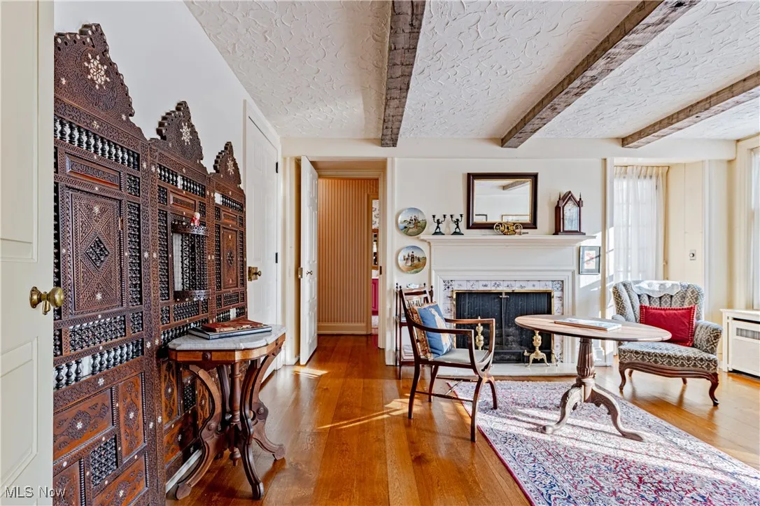 Living room with beamed ceiling, a textured ceiling, and hardwood / wood-style floors