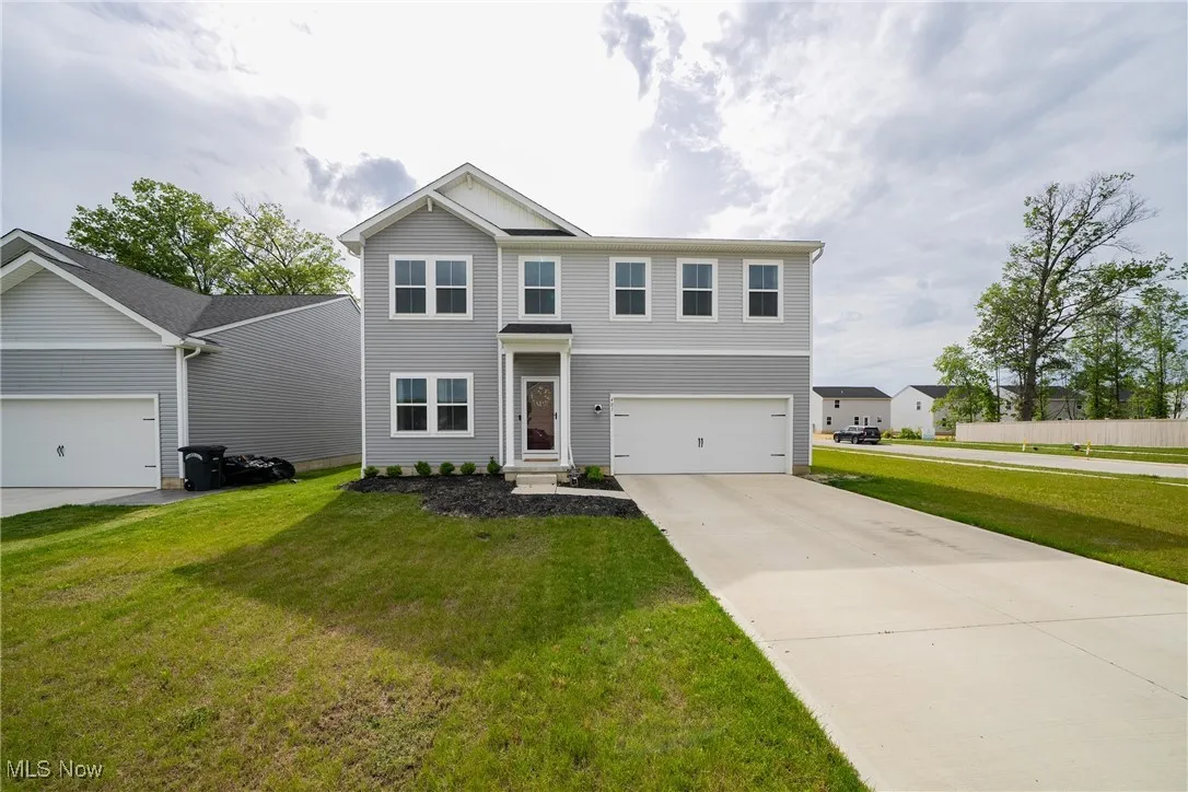 View of front facade with a front yard, concrete driveway, and a garage