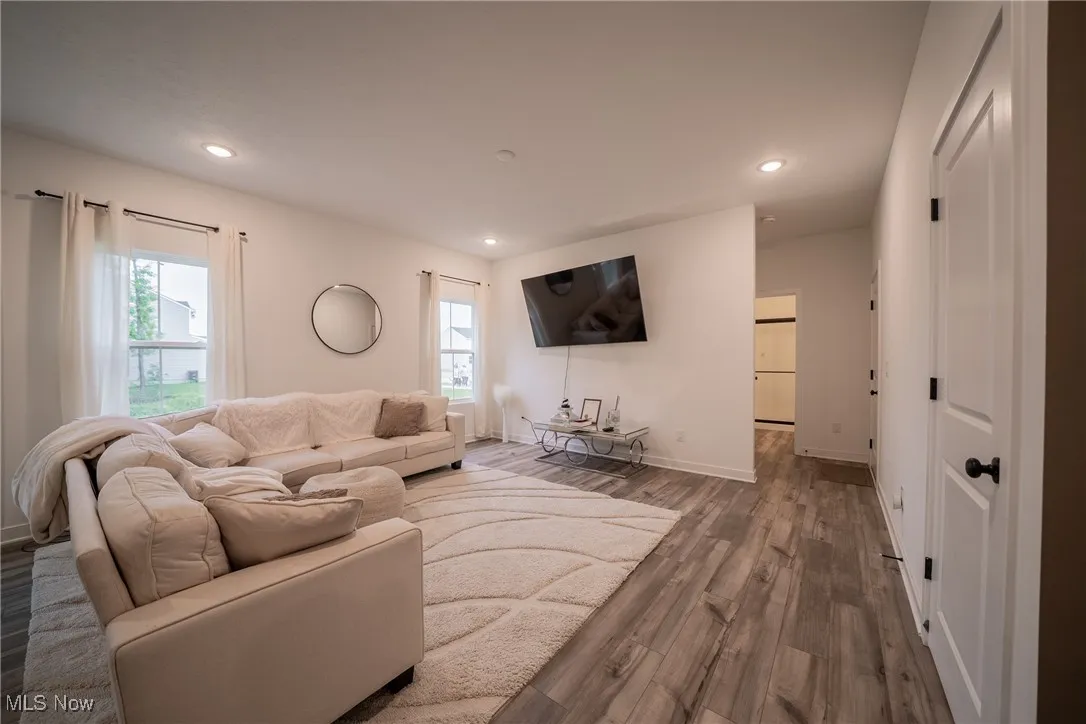 Living room with wood finished floors, recessed lighting, and baseboards