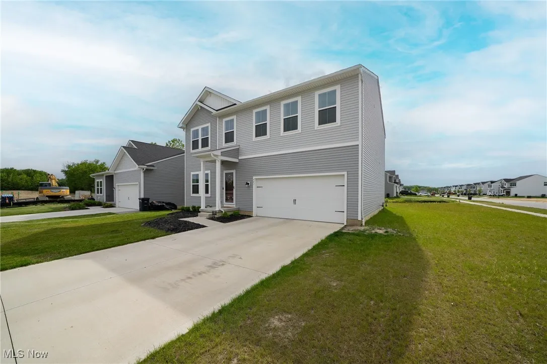 View of front facade featuring driveway, a front lawn, and a garage