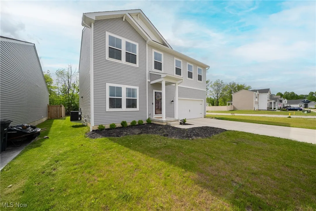 View of front of home featuring driveway, cooling unit, and an attached garage