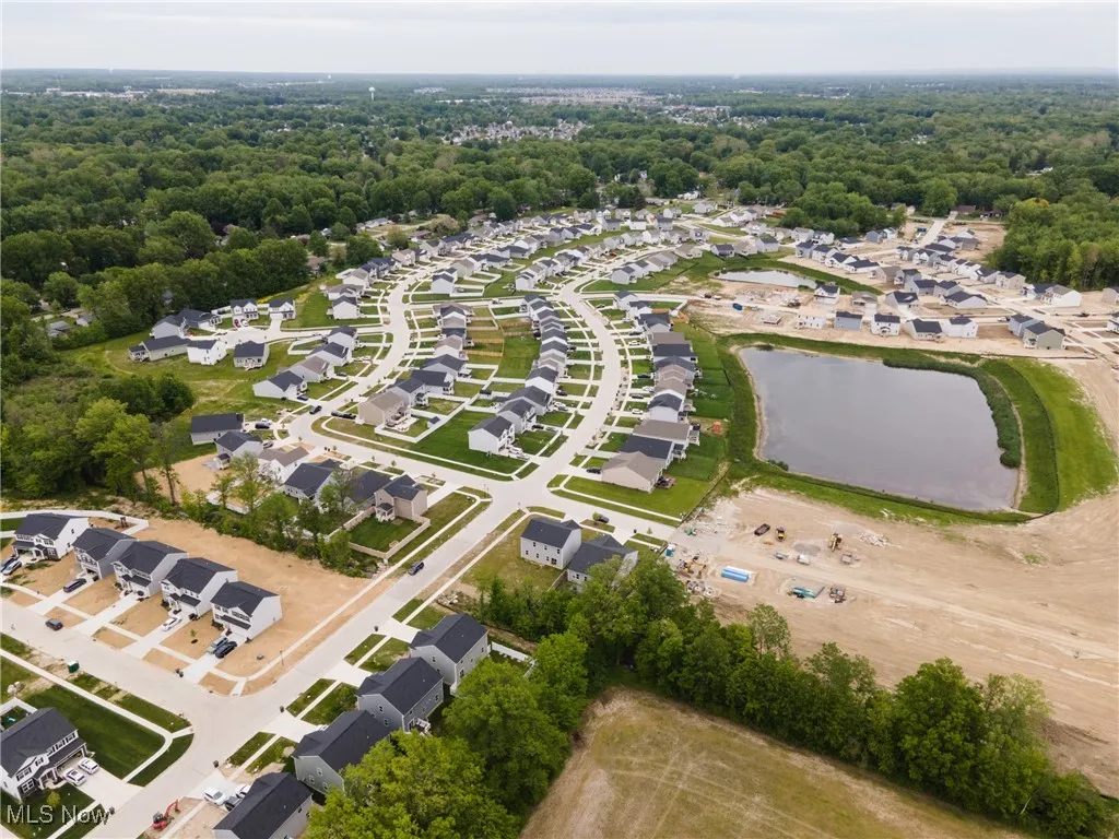Aerial view of property's location featuring a large body of water, nearby suburban area, and a forest