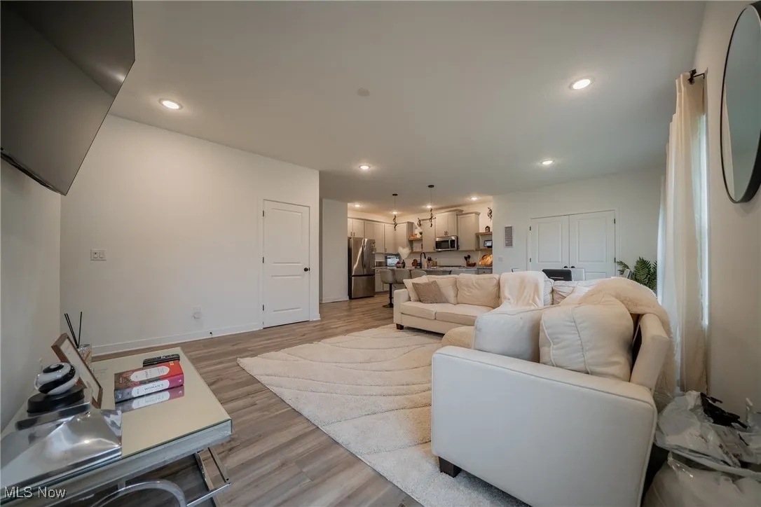 Living room with light wood-style flooring, recessed lighting, and baseboards