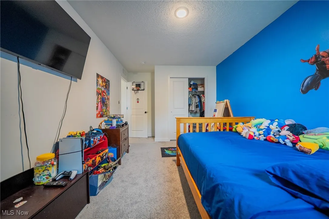 Bedroom with a textured ceiling, a closet, and carpet floors