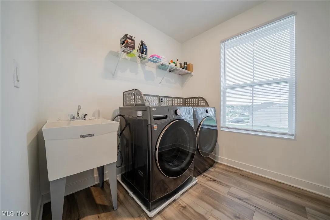 Laundry room featuring wood finished floors, separate washer and dryer, and baseboards