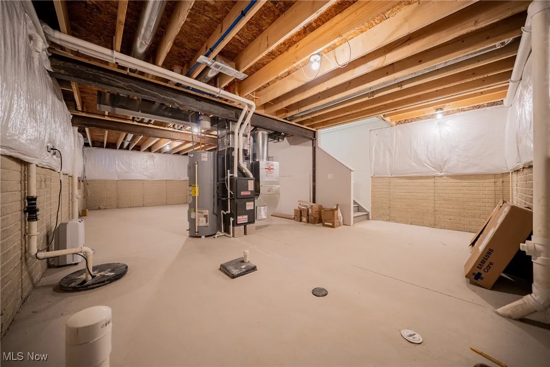 Unfinished basement with water heater, heating unit, and stairs