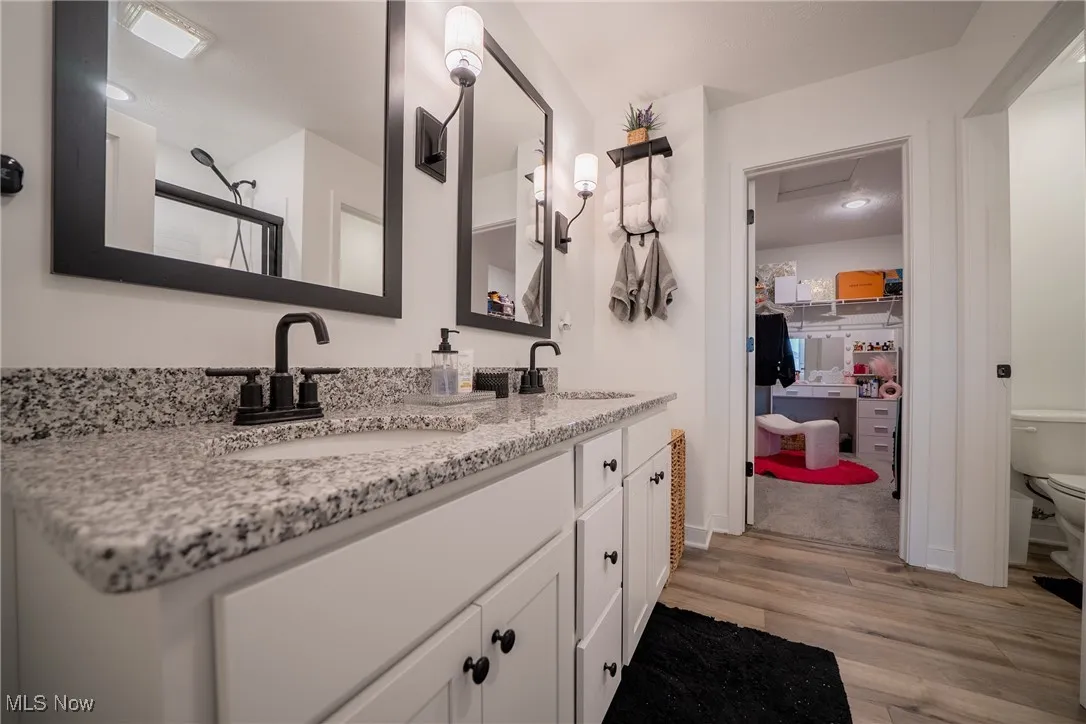 Full bath featuring wood finished floors, toilet, and double vanity