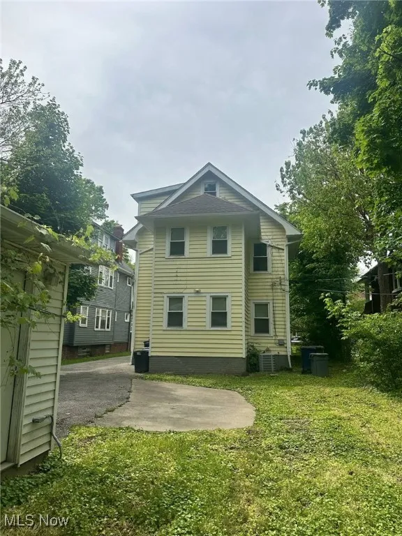 Back of property featuring a lawn, central AC unit, and a patio