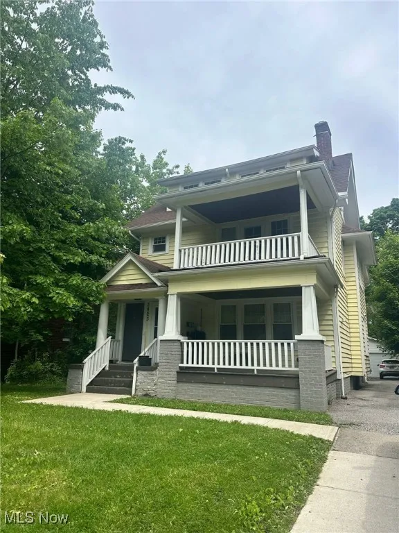 Craftsman-style house featuring a balcony, a chimney, covered porch, and a front yard