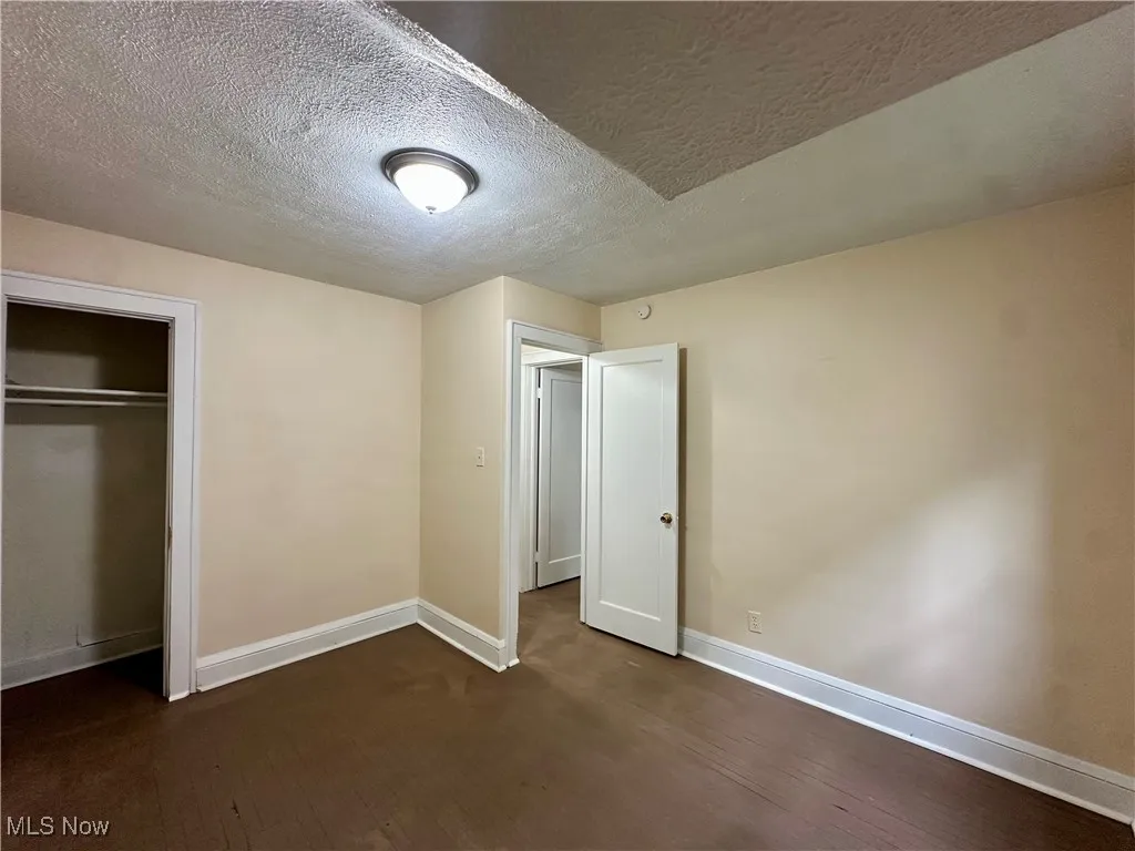 Unfurnished bedroom with baseboards, a closet, and a textured ceiling