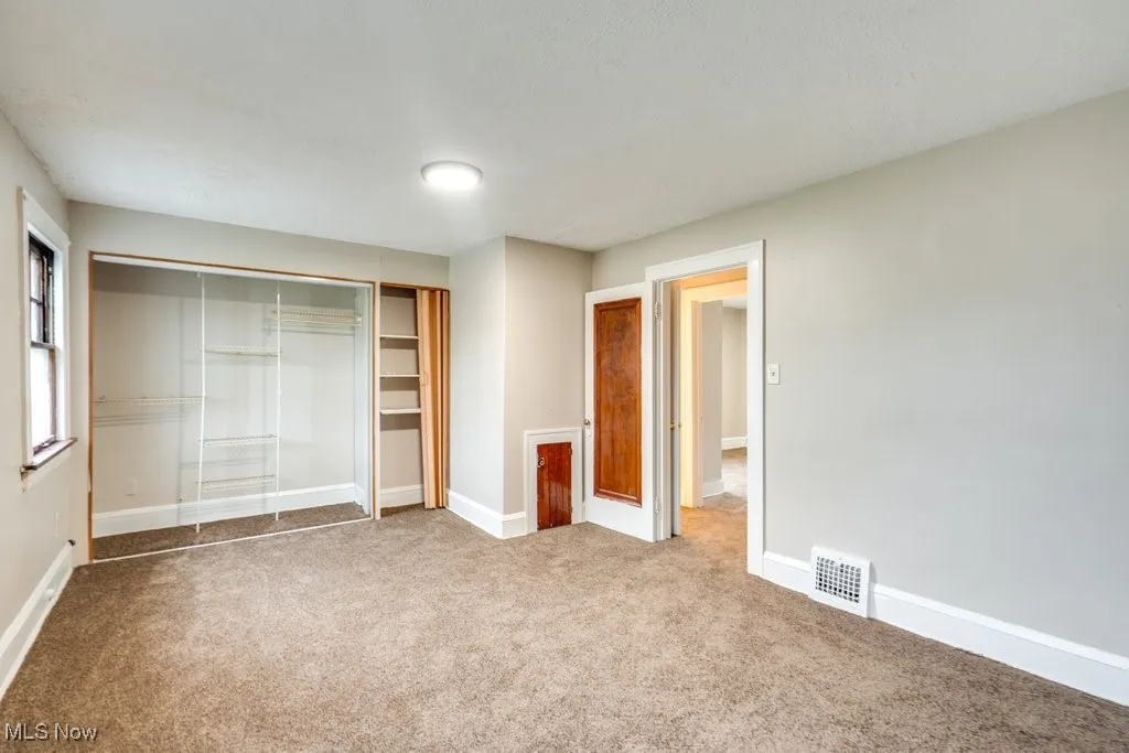 Unfurnished bedroom with carpet, a closet, and baseboards