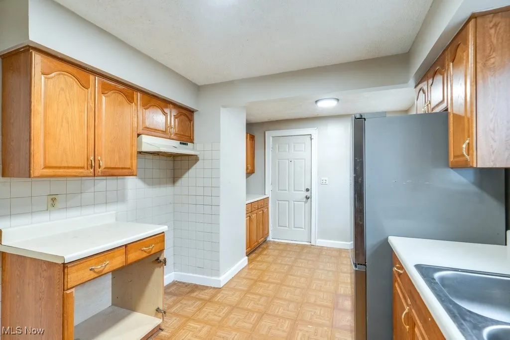 Kitchen featuring freestanding refrigerator and brown cabinetry