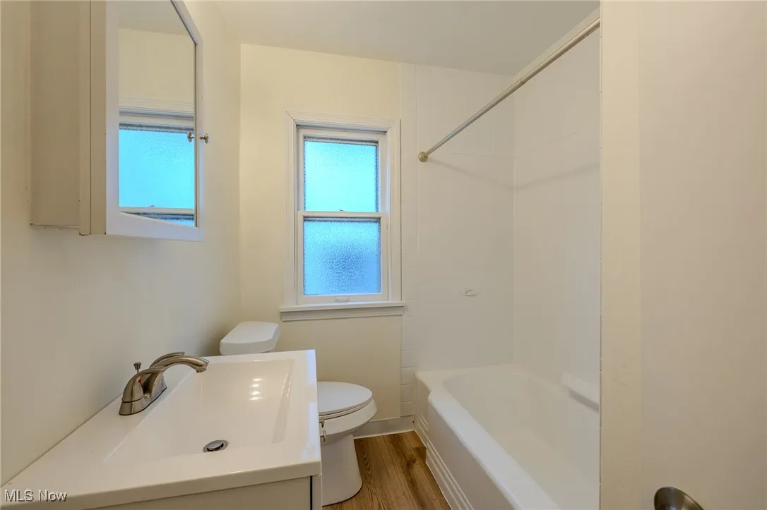 Full bathroom featuring toilet, vanity, bathing tub / shower combination, wood finished floors, and​​‌​​​​‌​​‌‌​‌‌​​​‌‌​‌​‌​‌​​​‌​​ baseboards