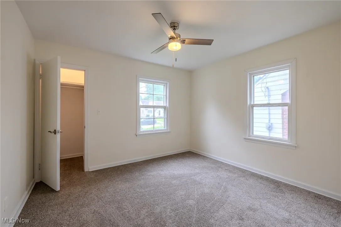 Unfurnished bedroom with a walk in closet, carpet, and baseboards