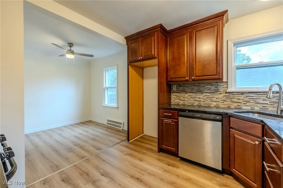 Kitchen with stainless steel dishwasher, a sink, light wood-style floors, tasteful backsplash, and ceiling fan