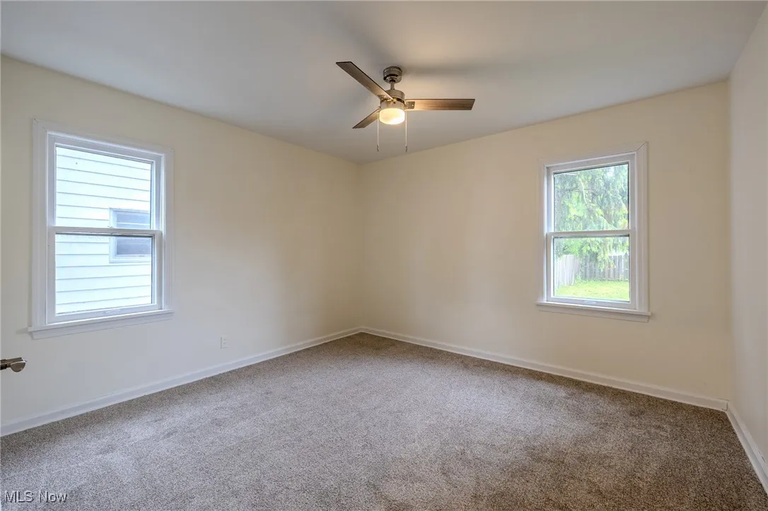 Unfurnished room featuring carpet floors, ceiling fan, and baseboards