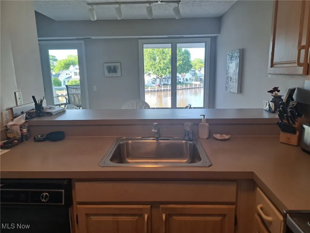 Kitchen with a sink, plenty of natural light, track lighting, and a water view
