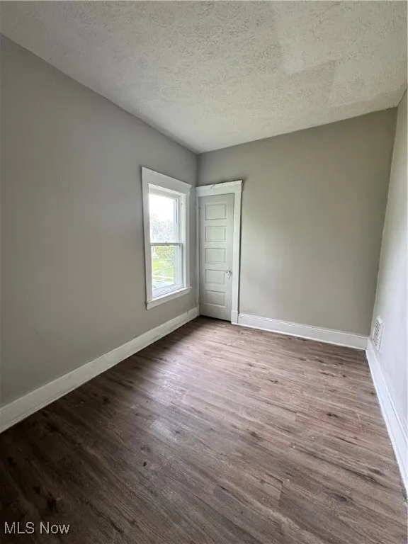 Unfurnished bedroom featuring baseboards, dark wood finished floors, and a textured ceiling