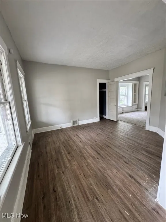 Unfurnished room with dark wood-style flooring and baseboards