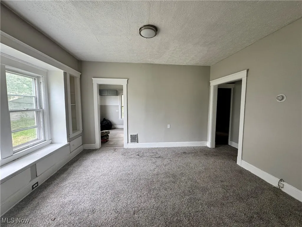 Spare room featuring carpet flooring, a textured ceiling, and baseboards