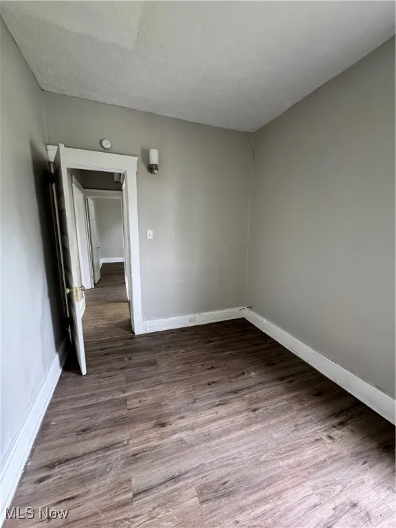 Unfurnished room with baseboards, dark wood finished floors, and a smoke detector