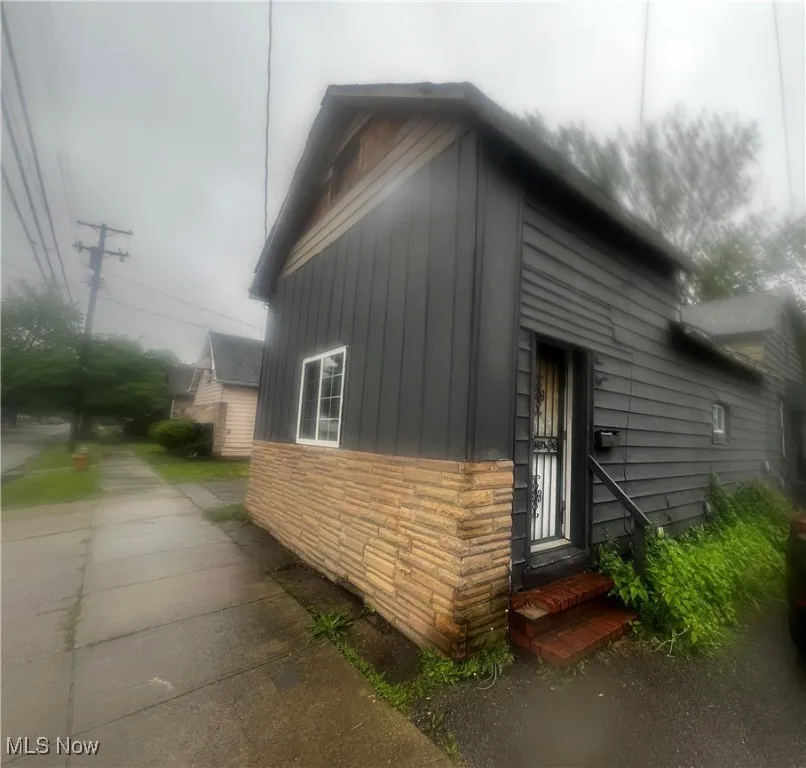 View of side of home with entry steps and stone siding