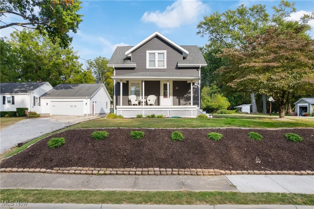 View of front of property with a porch, a front yard, and an outdoor structure