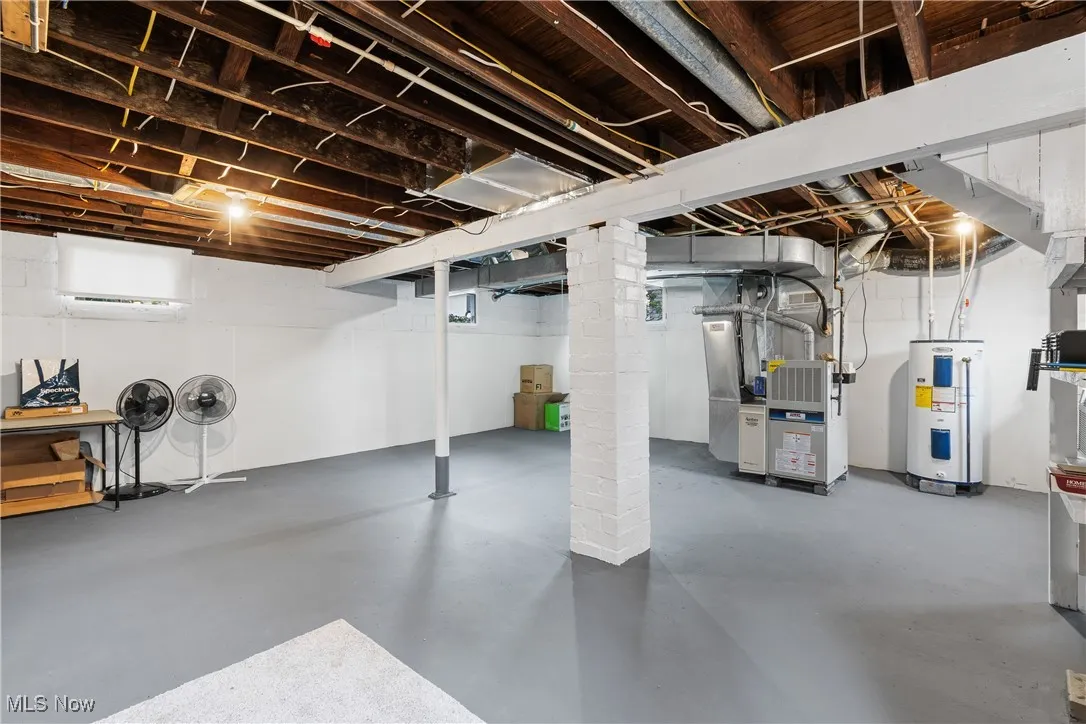 Unfinished below grade area with electric water heater and heating unit