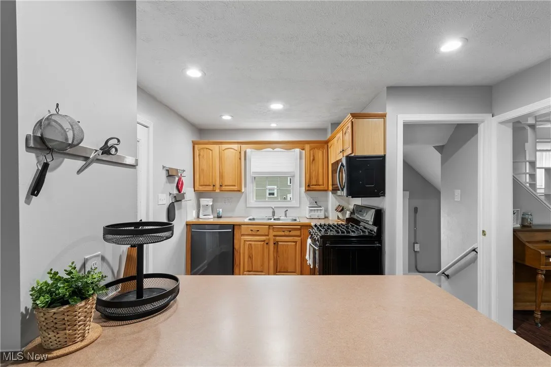Kitchen with gas range, dishwasher, a sink, recessed lighting, and light countertops