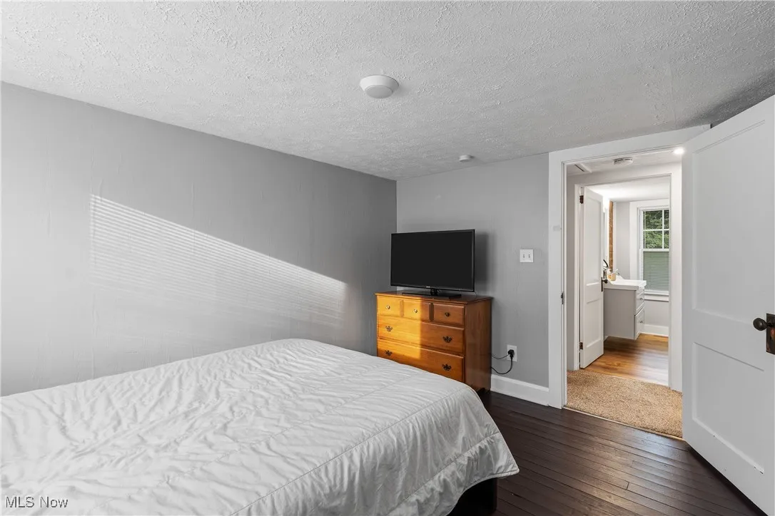 Bedroom featuring dark wood finished floors, a textured ceiling, and baseboards
