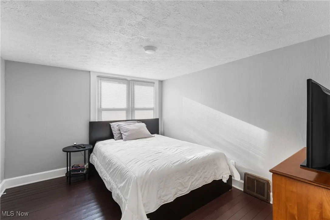 Bedroom featuring dark wood finished floors, a textured ceiling, and baseboards