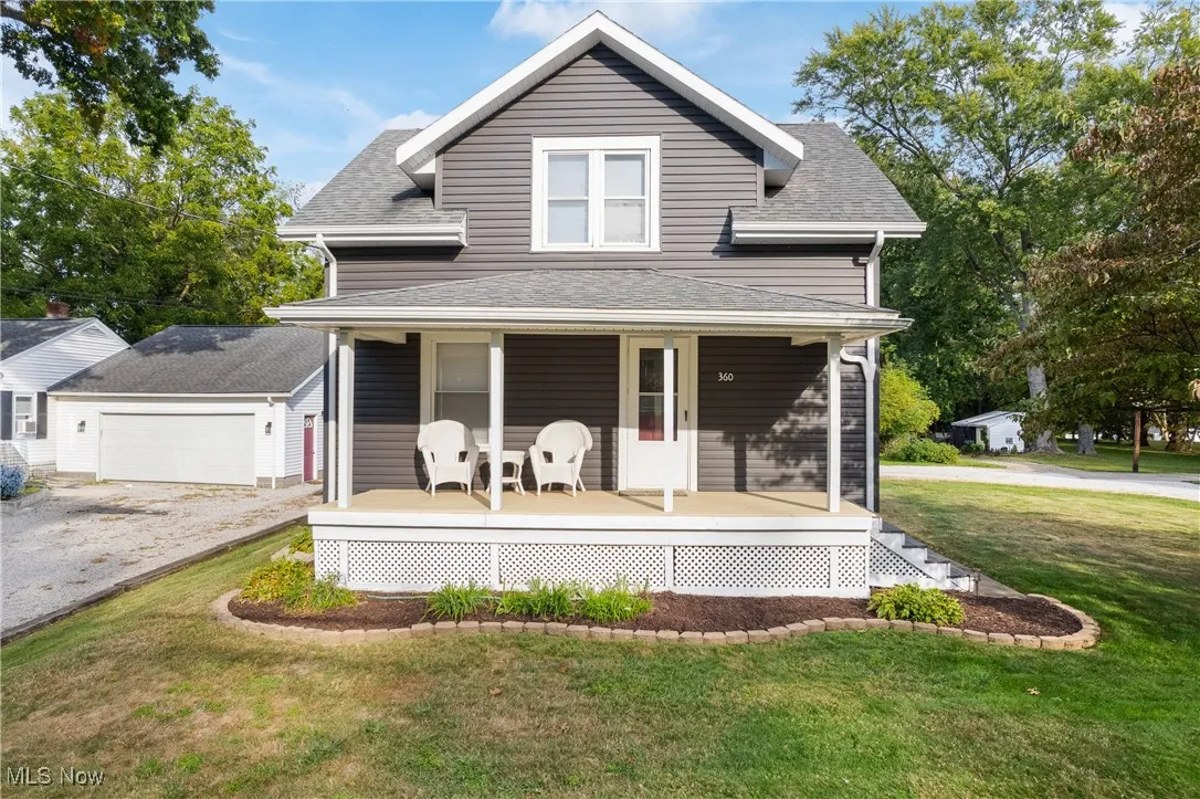 View of front of home featuring covered porch, a front yard, a garage, and roof with shingles