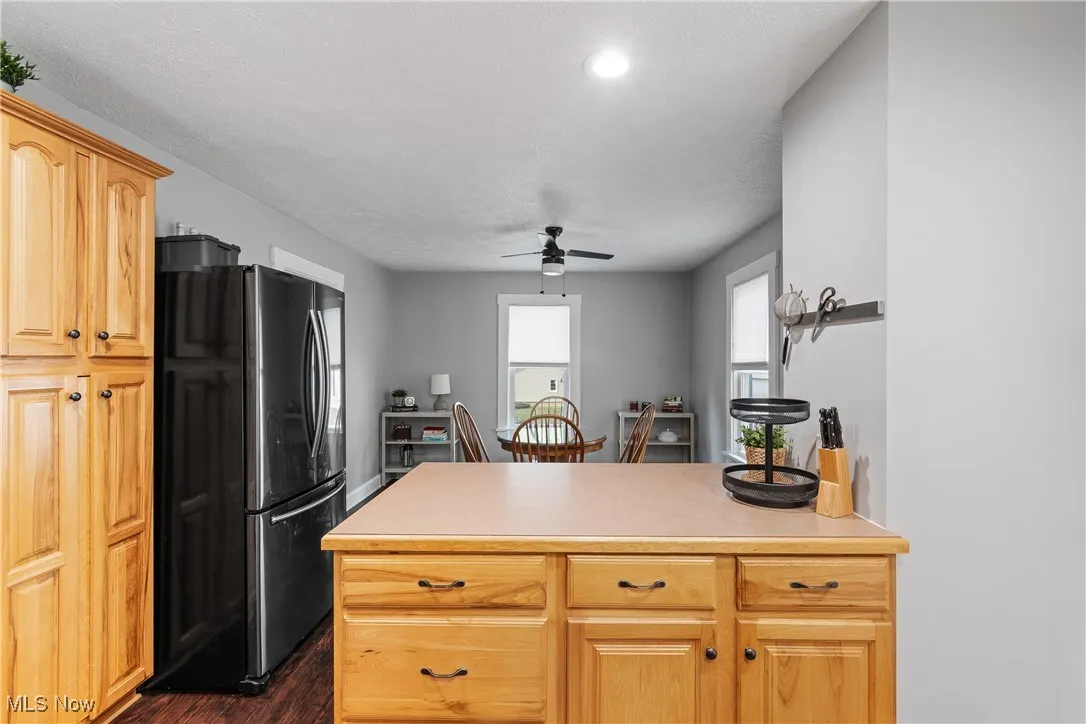 Kitchen featuring freestanding refrigerator, dark wood-type flooring, a ceiling fan, light countertops, and a peninsula