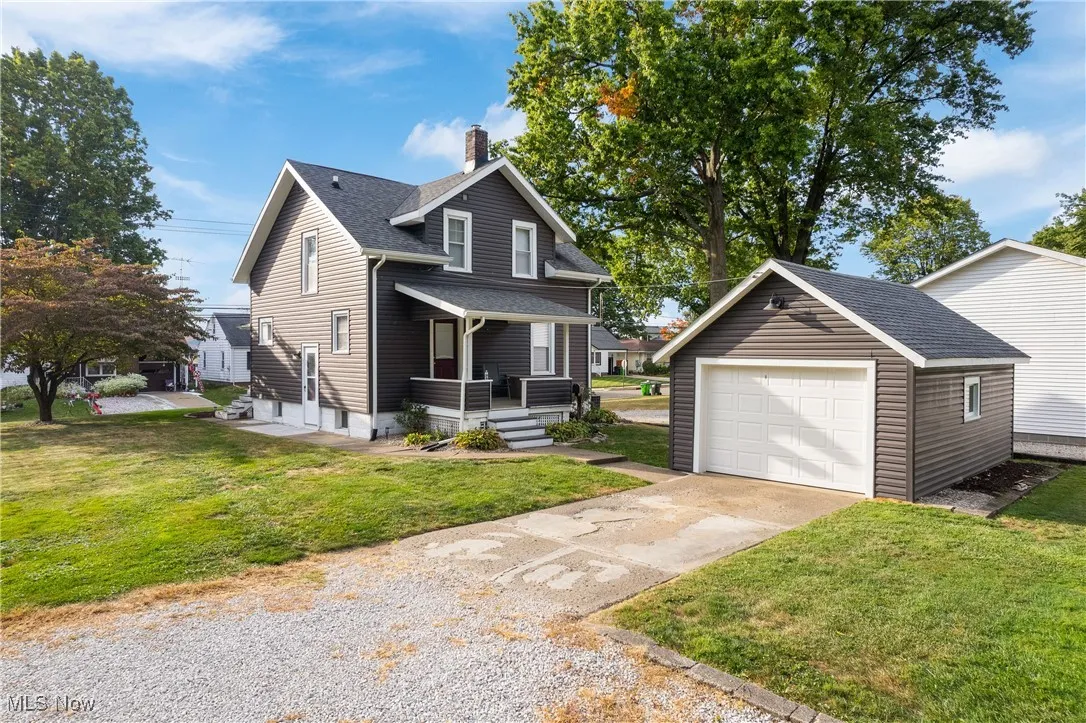 View of rear
 facade featuring a chimney, driveway, a shingled roof, and a front lawn