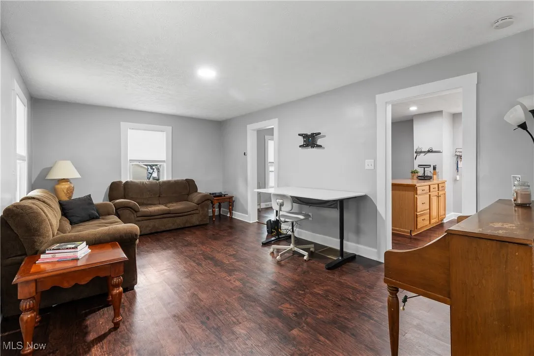 Living area featuring dark wood-type flooring, baseboards, and recessed lighting
