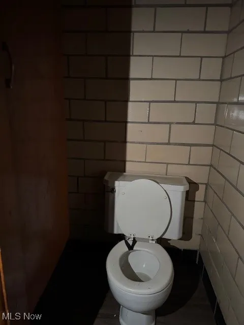 Bathroom featuring toilet and tile walls
