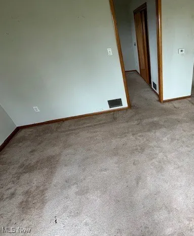 Carpeted spare room with visible vents and baseboards